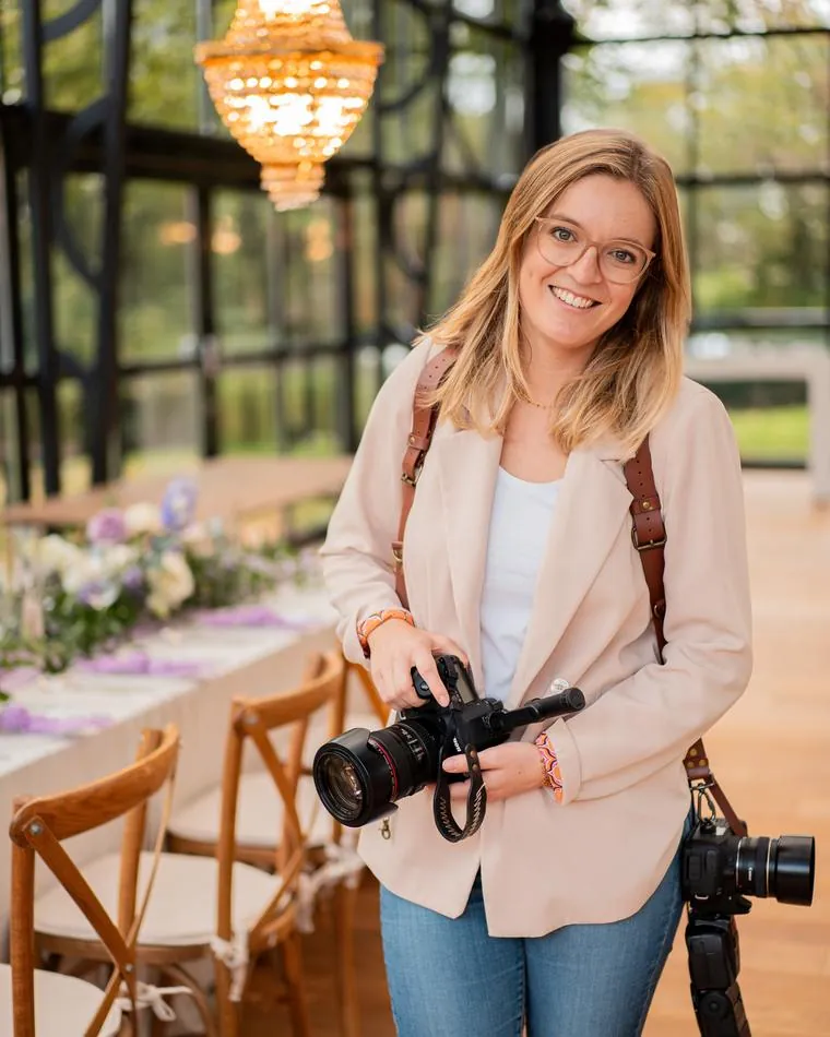 Porträt der Hochzeitsfotografin Anna-Lena Woll mit Kamera im lichtdurchfluteten Greenhouse